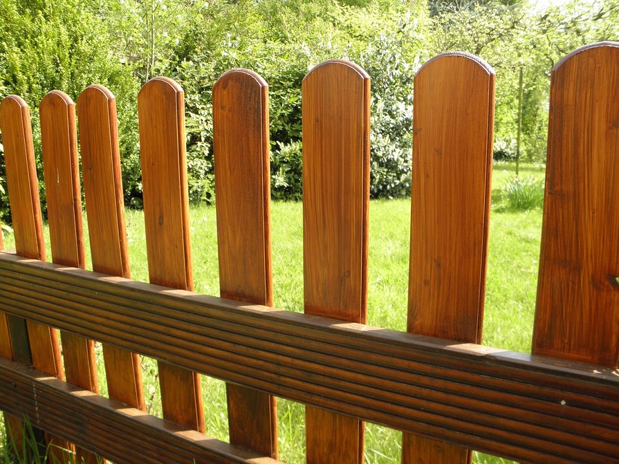 Gartenzaun aus Holz vor grüner Wiese